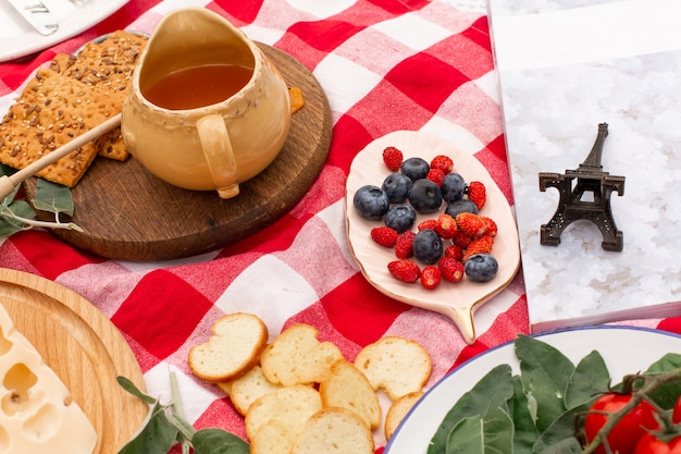 Stylish picnic on the green lawn. fresh croissants and a teapot with tea on a bedspread near a wicker female hat. instagram content Premium Photo