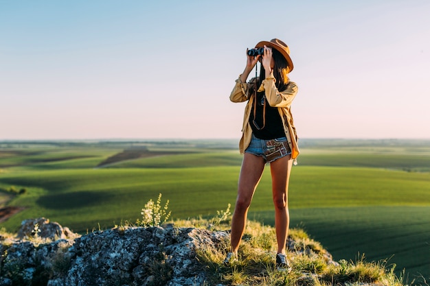 Stylish young woman looking through binoculars | Free Photo
