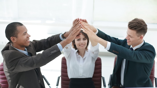 Successful business team giving high five ,sitting behind a desk Premium Photo