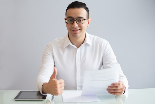 Successful young businessman with document showing thumbs up Free Photo