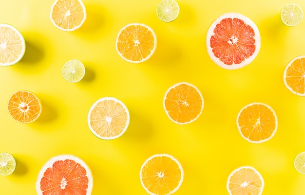 パステルイエローの紙にオレンジ レモン ライムから作られた夏の組成 プレミアム写真