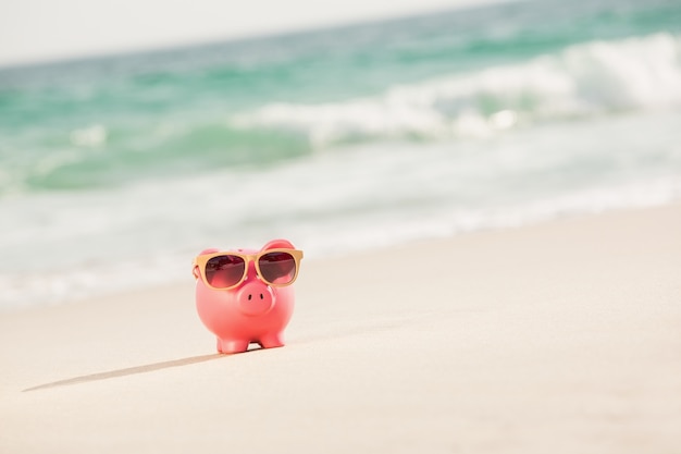 Summer piggy bank with sunglasses on sand 1252 572