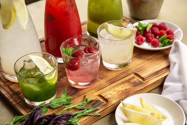 Summer soft drinks, a set of lemonades. lemonades in jugs on the table, the ingredients of which they are made are arranged around. Premium Photo