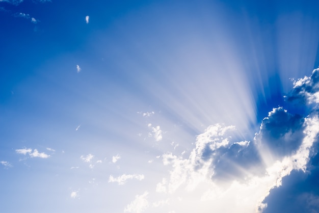 Premium Photo | Sunbeams rising from a large cloud in intense blue sky ...