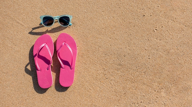 Free Photo | Sunglasses and beach slippers on sand