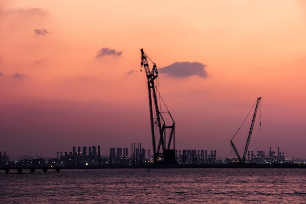 アラブ首長国連邦 ドバイ港の夕日 明るい空を背景にクレーンのシルエット プレミアム写真