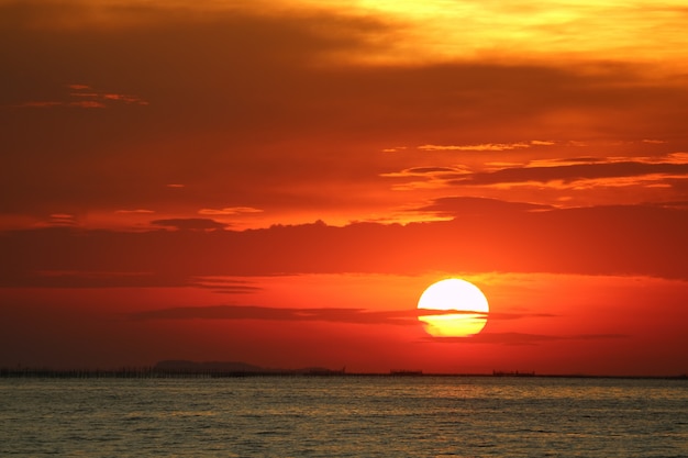 地平線の海に赤黄色の空バックソフト夕方の雲に沈む夕日 プレミアム写真