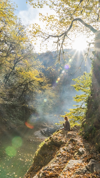 Premium Photo | Sunshining in autumn forest. girl sits on the cliff ...