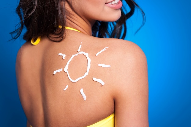 Suntan lotion on woman's arm in sun shape Free Photo