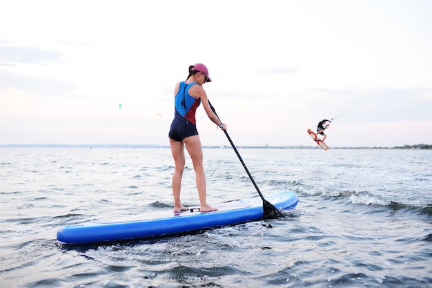 海のsupボードと10代の女の子 パドルサーフィンアクティビティ プレミアム写真