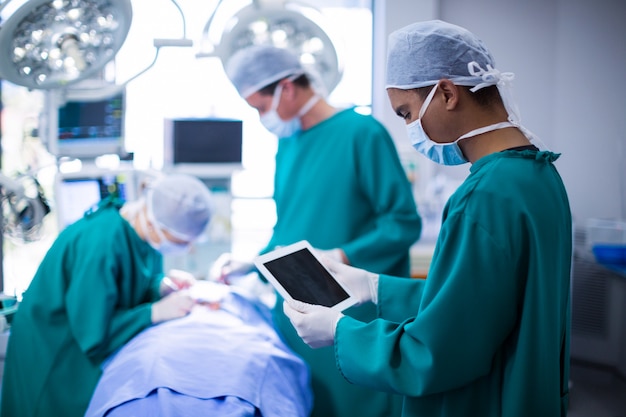 Surgeon using digital tablet in operation theater Free Photo