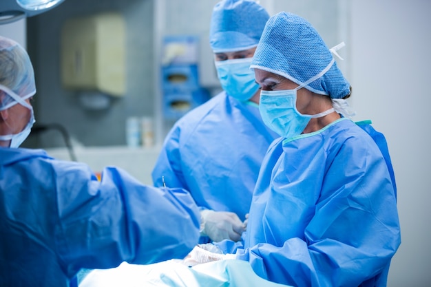 Surgeons performing operation in operation room Free Photo