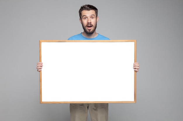 Surprised man showing empty white board Free Photo