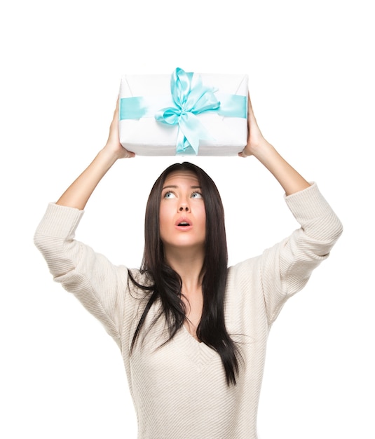 Premium Photo | Surprised young woman holding overhead a box with gift