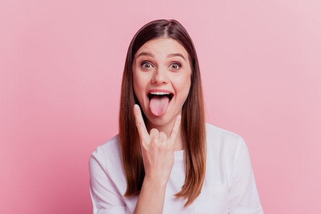 Premium Photo | Surprised young woman show horns stick tongue out mouth ...