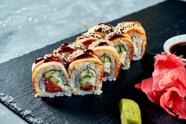 Premium Photo Sushi Roll Golden Dragon With Eel Salmon Philadelphia Cheese And Unagi Sauce On A Black Slate Board