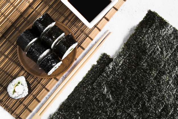 Sushi rolls and soy sauce on bamboo mat near seaweed Free Photo