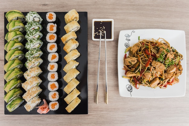 Sushi rolls with yakisoba and soy sauce on a wooden table Premium Photo