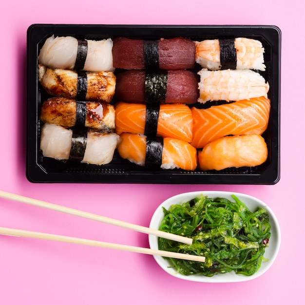 Sushi set box with seaweed salad on a rose background Free Photo