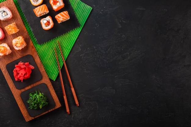 Sushi set with wasabi and ginger on black stone tray on black table. top view Premium Photo