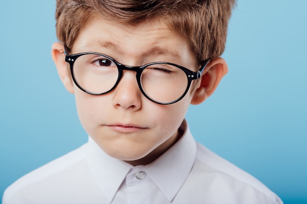 Premium Photo | Suspicious little boy with one eyes closed glasses look ...