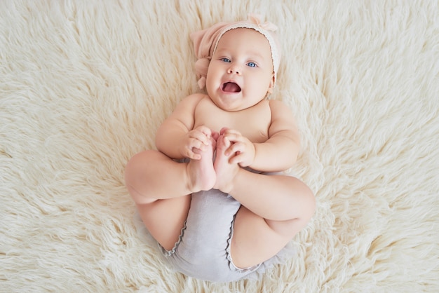 子供部屋のベッドの上の甘い面白い赤ちゃん 6ヶ月座ってクロールのかわいい女の子 プレミアム写真