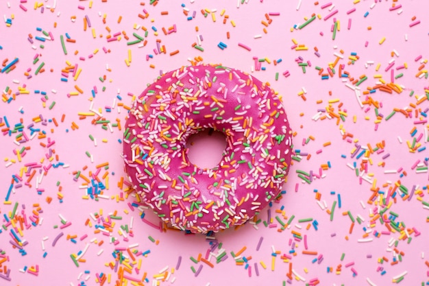 Premium Photo Sweet Pink Donut With Multicolored Sprinkles On A Pink Surface Flat Lay 