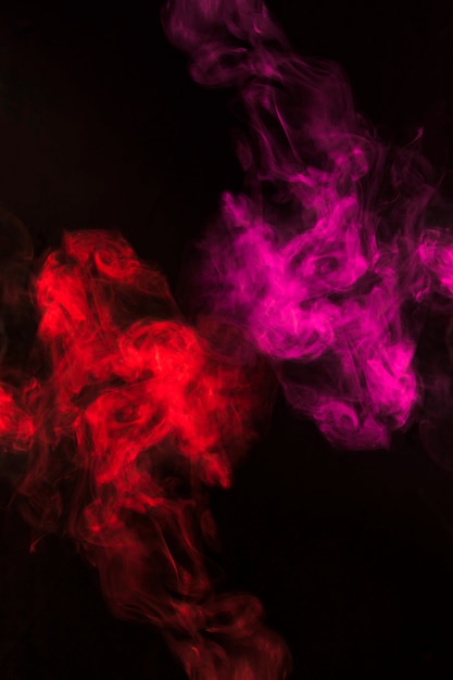 黒の背景に赤とピンクの煙霧の旋回 無料の写真