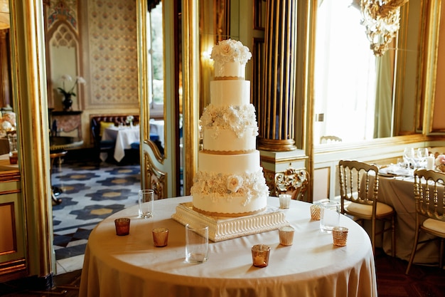 背の高い白い疲れたウェディングケーキが丸いテーブルに立つ 無料の写真