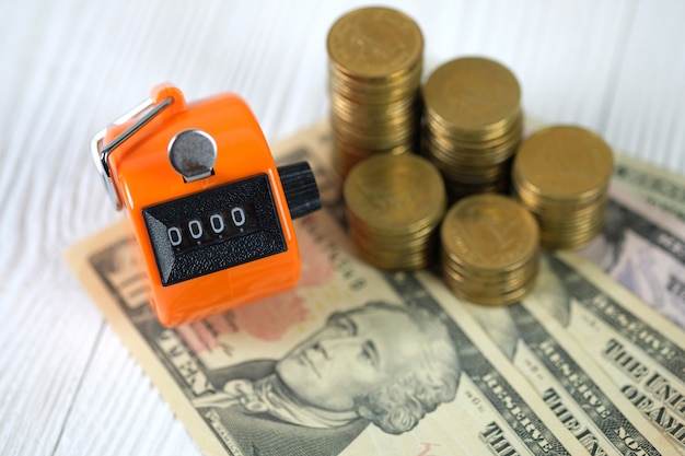Tally counter or counting machine with 0000 number, coin and banknote on wood Premium Photo