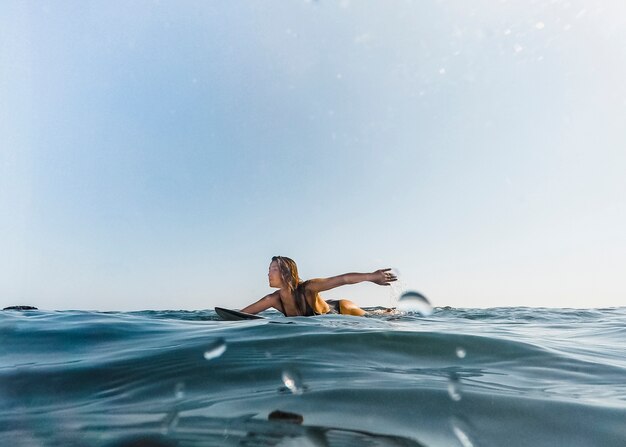 Tanned woman swimming on surfboard in water Free Photo