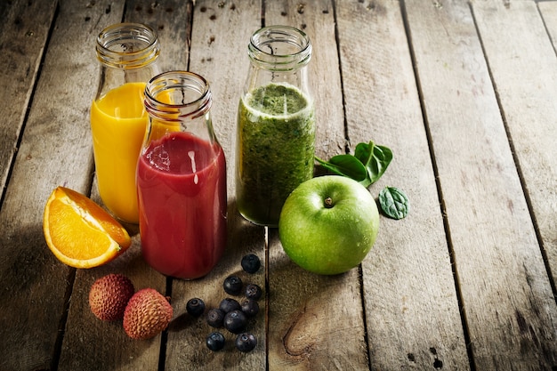 Tasty colorful fresh homemade smoothies in glass jars on wooden table. Healthy, detox concept. Free Photo