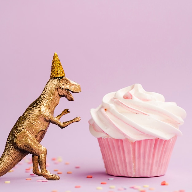 Tasty muffin and dinosaur with birthday hat Free Photo
