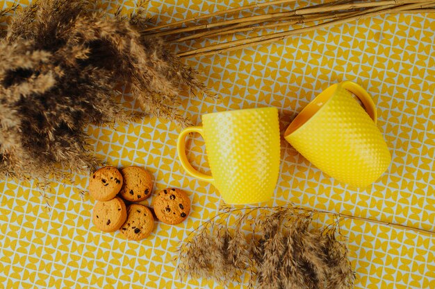 Premium Photo Tea Time Two Yellow Tea Cups And Cookies With Chocolate On The Table Brown Cookies And Dried Flowers On The Table