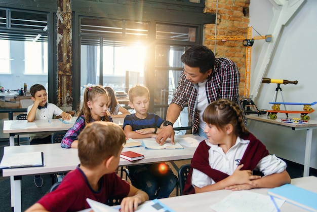 Premium Photo | Teacher helping school kids with test tasks in ...