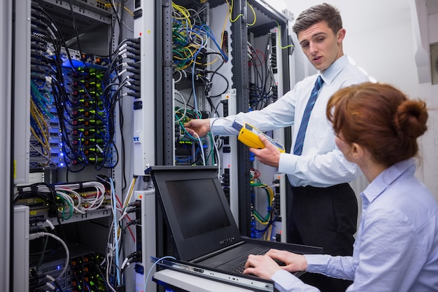 Premium Photo | Team of technicians using digital cable analyser on servers