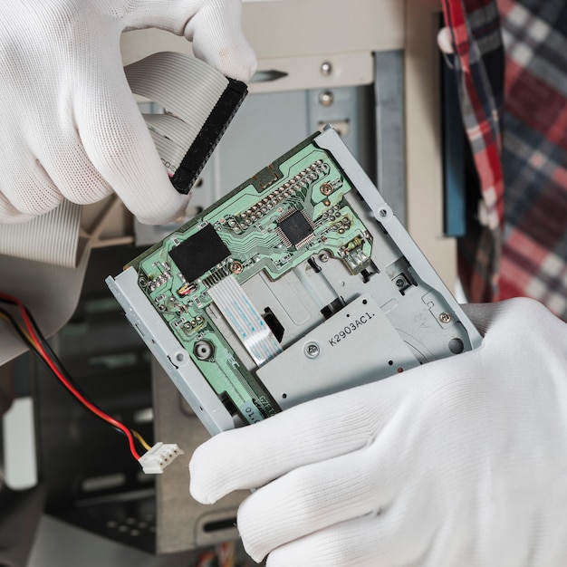 Technician inserting ide computer cable in hard disk drive Free Photo