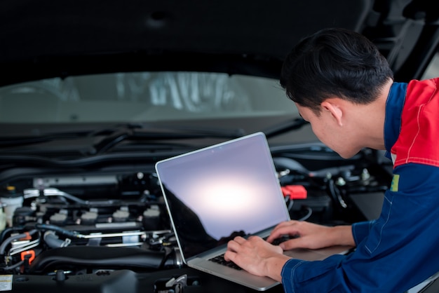 技術者がガレージで車をチェックして修理する自動車修理工場の技術者は コンピューターシステムを使用してエンジンの問題 車の修理サービス メンテナンスの概念 をチェックします プレミアム写真