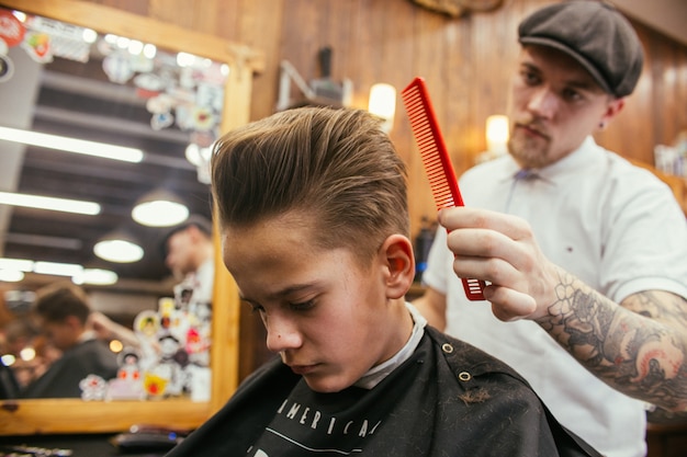 Teenage boy haircuts hairdresser in the barber shop ...