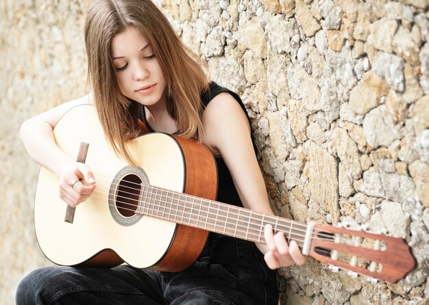 Premium Photo | Teenage girl with a guitar against a brown wall