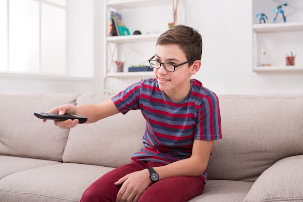 Premium Photo | Teenager boy watching television, pointing with remote ...