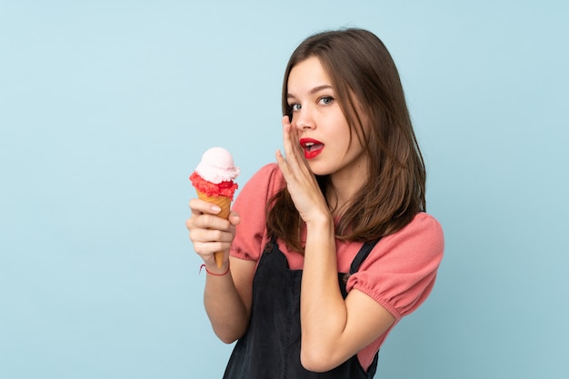 Premium Photo Teenager Girl Holding A Cornet Ice Cream On Blue Whispering Something