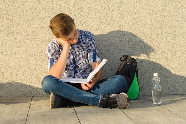 Teenager schoolboy reads textbook Premium Photo