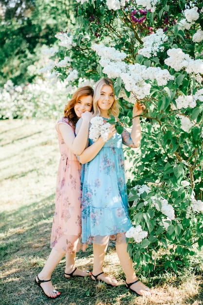 Tender and cheerful twins sisters in beautiful dresses