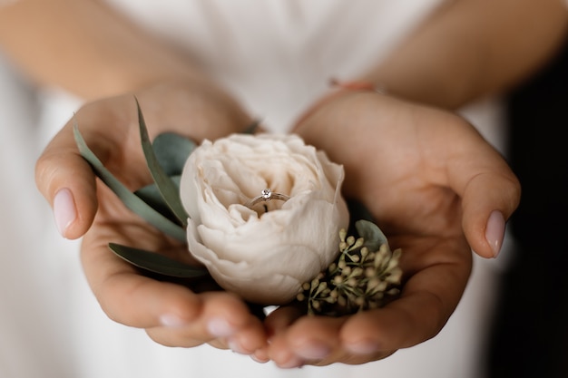 Tender eustoma flower with engagement ring with tiny diamond in hands of bride Free Photo