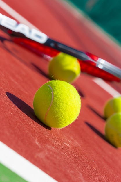 Premium Photo | Tennis balls and racket on the grass court