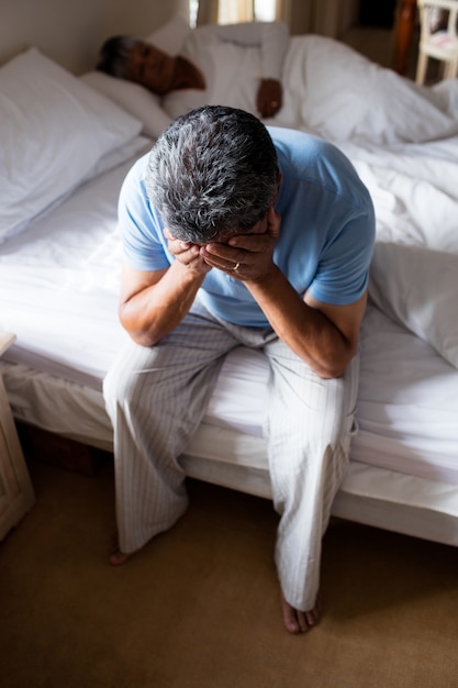 Premium Photo | Tensed senior man sitting on bed