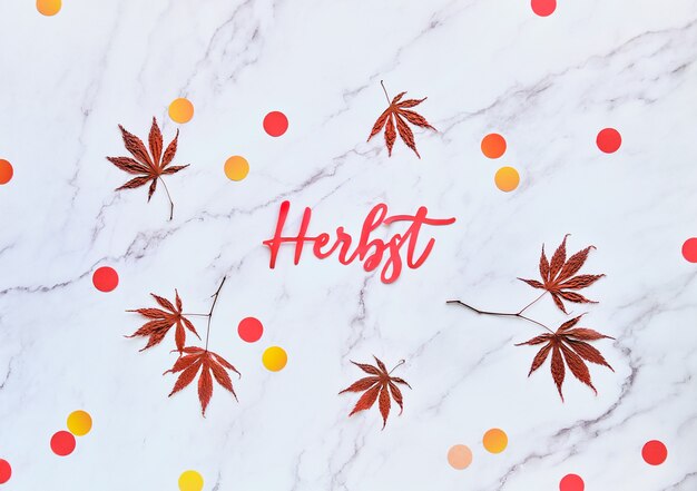 テキストherbstはドイツ語で秋を意味します 自然のカエデの葉と紙吹雪の最小限の秋の季節背景 プレミアム写真