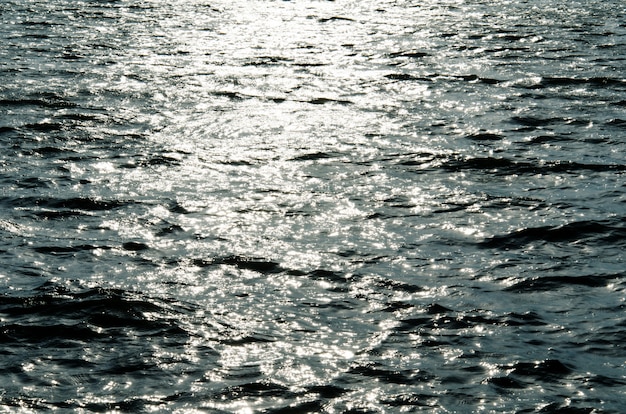 Texture of rippled sun-dappled river water reflecting sunrays at sunset making shiny sun dogs, toned blue Premium Photo