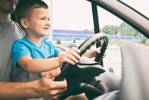 子供は車の中で父親の膝の上に座って 車の運転方法を学んでいます プレミアム写真